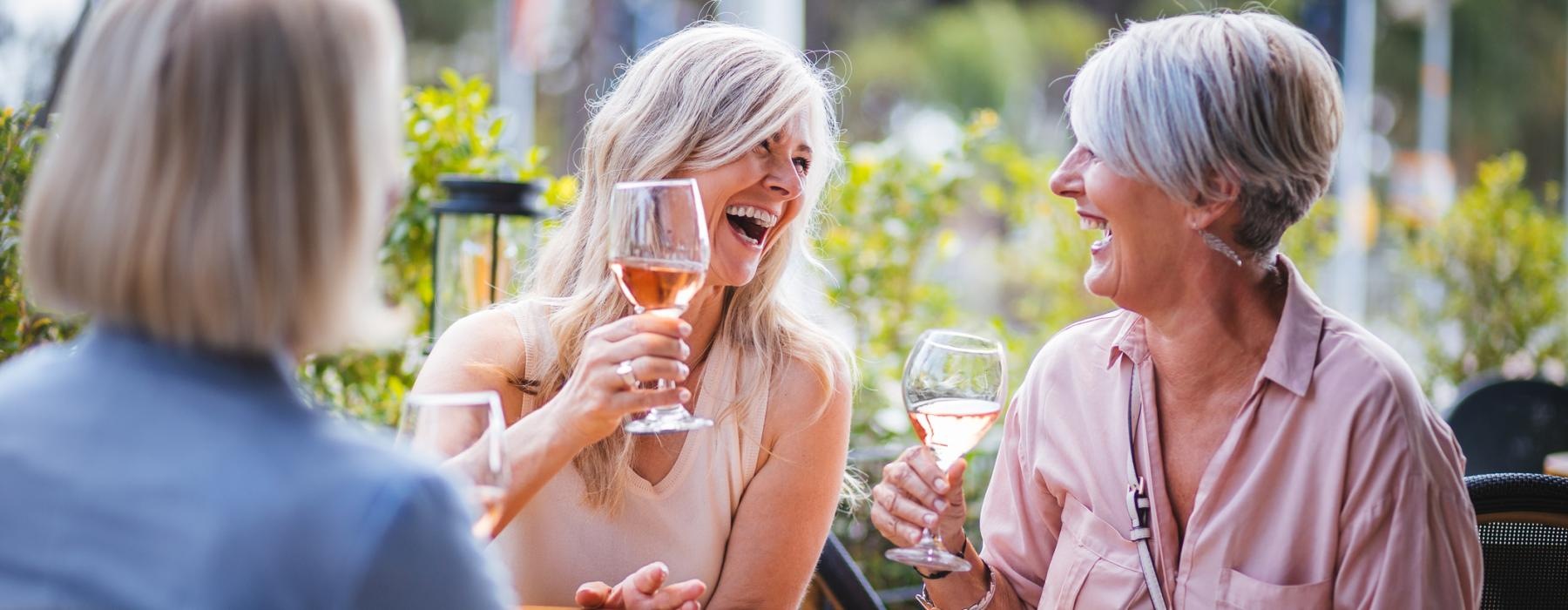 a few women laughing and drinking wine